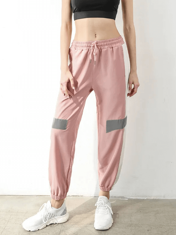 Woman wearing pink stylish athletic elastic waist patchwork joggers with contrast stripes, perfect for active wear and fashion-forward looks.